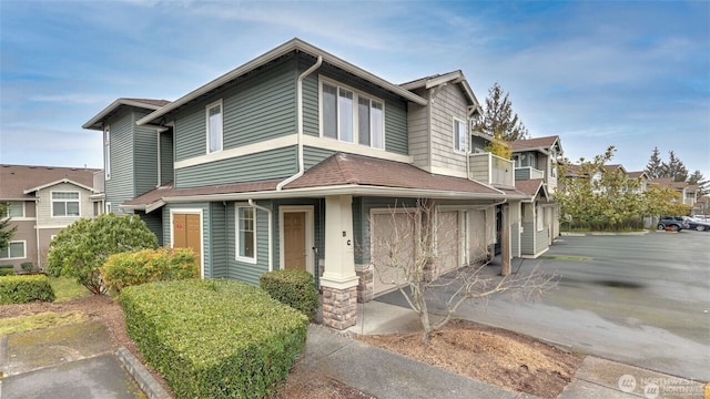 view of front of house with an attached garage, driveway, and roof with shingles