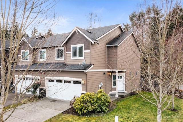 view of front facade with an attached garage, a shingled roof, a front yard, and driveway