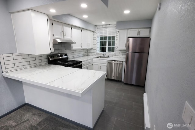 kitchen with appliances with stainless steel finishes, white cabinetry, a sink, a peninsula, and under cabinet range hood