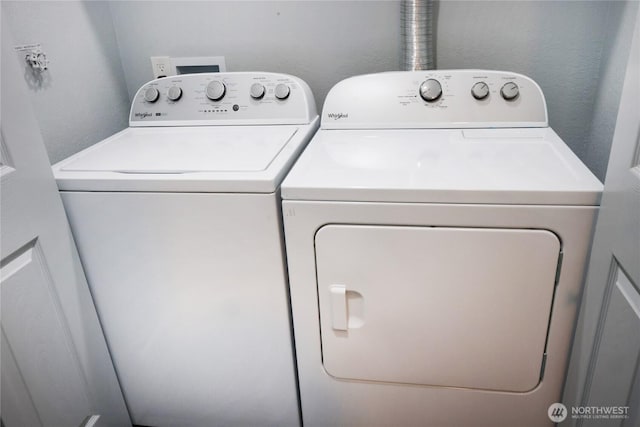 laundry room with a textured wall, laundry area, and washing machine and dryer