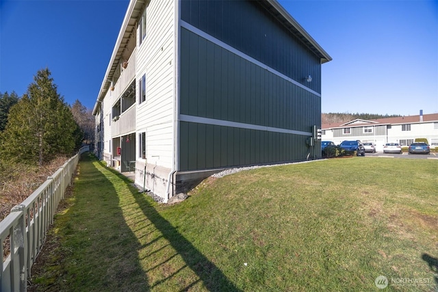 view of side of home with a yard and fence