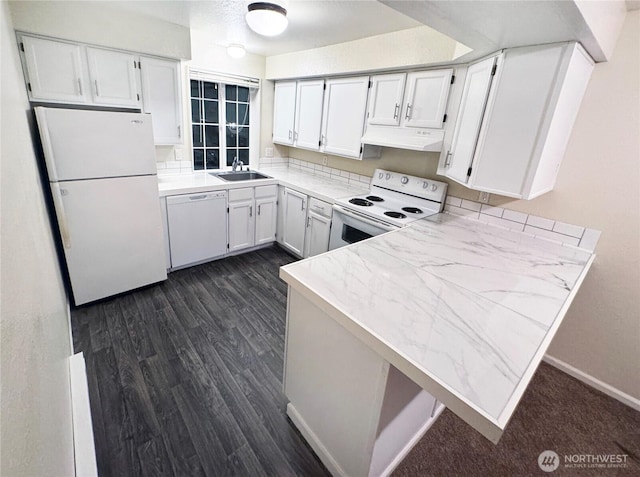 kitchen featuring dark wood-type flooring, a sink, a peninsula, white appliances, and under cabinet range hood