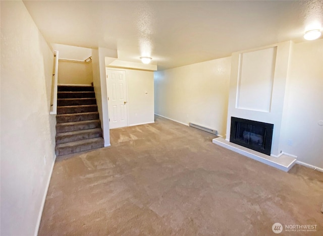 unfurnished living room featuring a fireplace with raised hearth, carpet, stairway, and baseboard heating