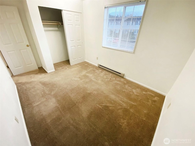 unfurnished bedroom with baseboards, a closet, a baseboard heating unit, and carpet flooring