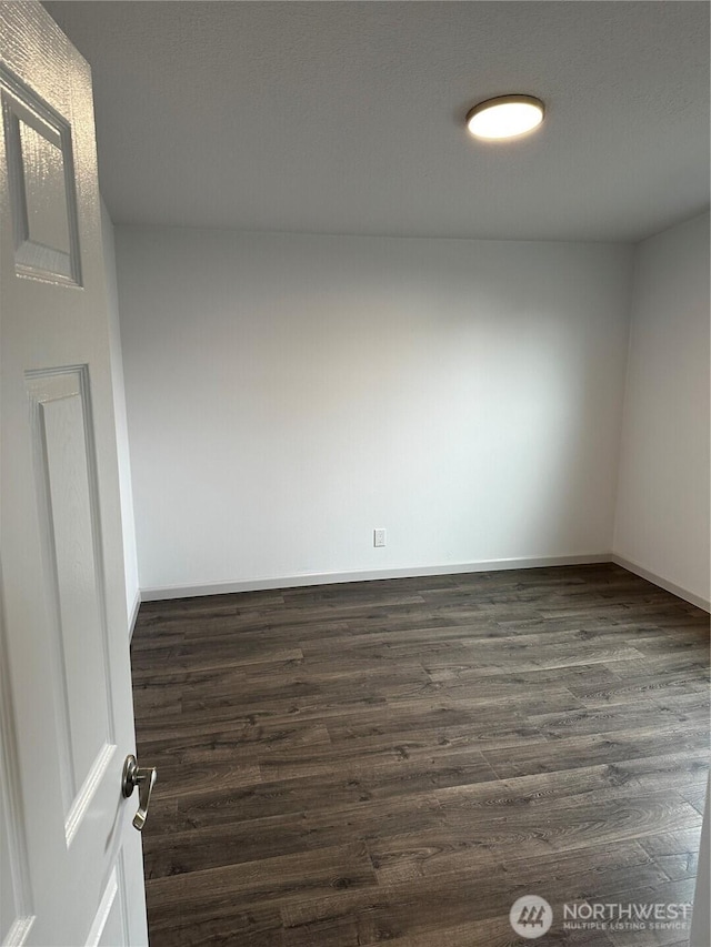 unfurnished room featuring dark wood-style flooring and baseboards