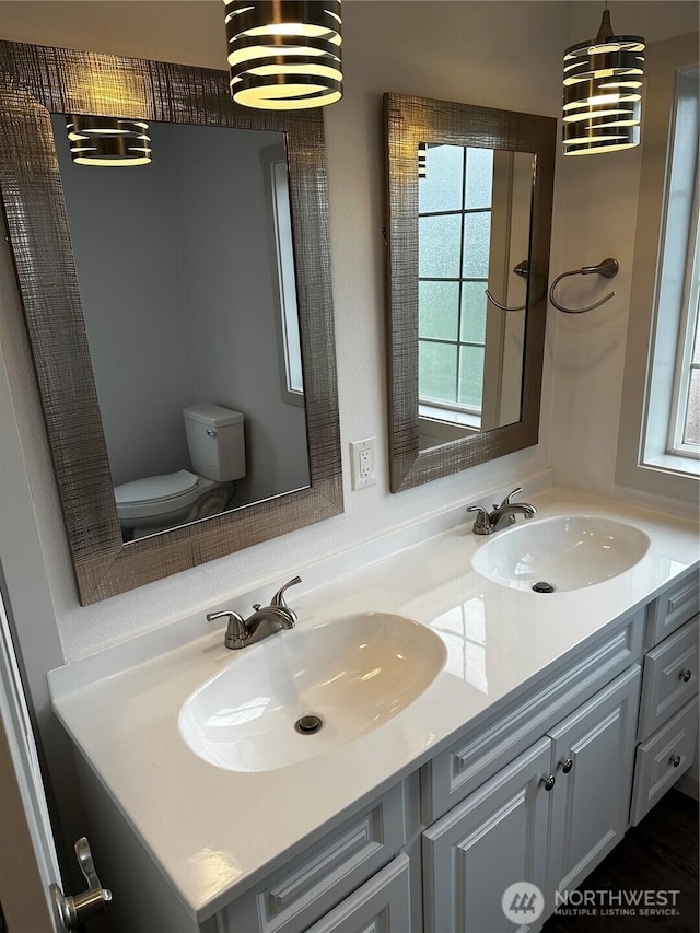 bathroom featuring double vanity, a sink, and toilet