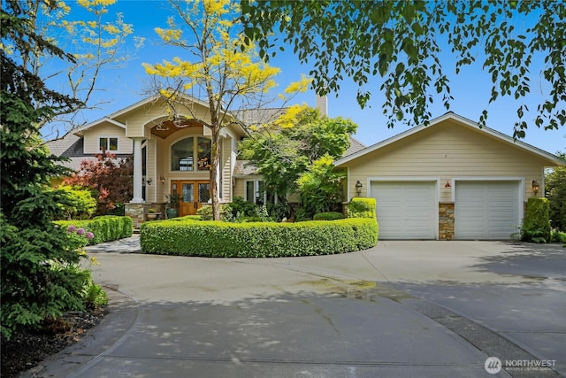 view of front of home featuring a garage, concrete driveway, and stone siding