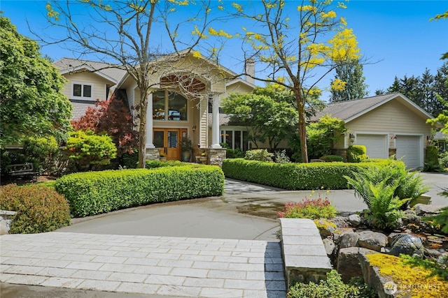 view of front of property with french doors, driveway, a chimney, and an attached garage