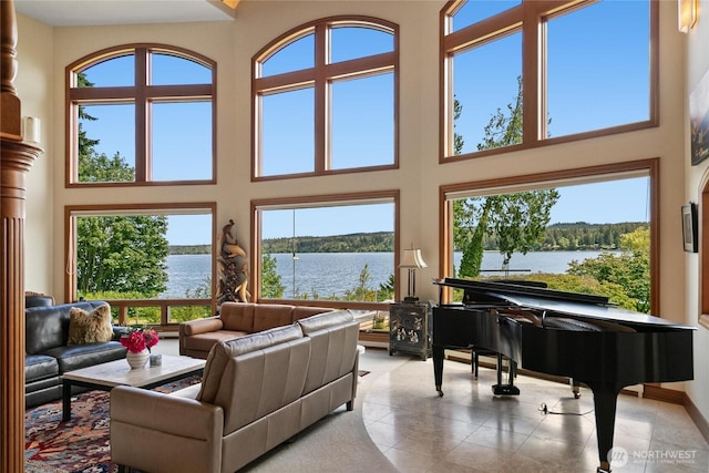 tiled living area with a water view and a high ceiling