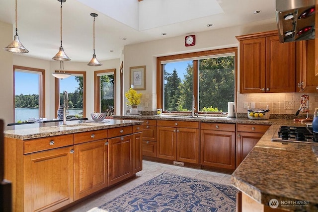 kitchen featuring a healthy amount of sunlight, backsplash, brown cabinets, and a sink