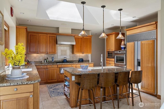 kitchen featuring appliances with stainless steel finishes, a sink, wall chimney range hood, backsplash, and a warming drawer