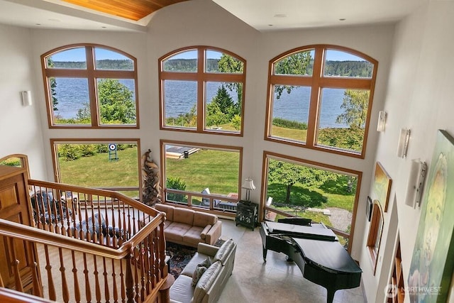 interior space with plenty of natural light, a high ceiling, and a water view