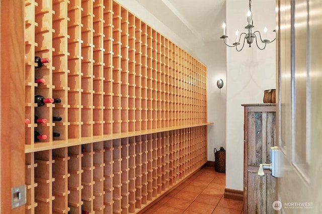 wine area featuring baseboards, tile patterned flooring, and a notable chandelier