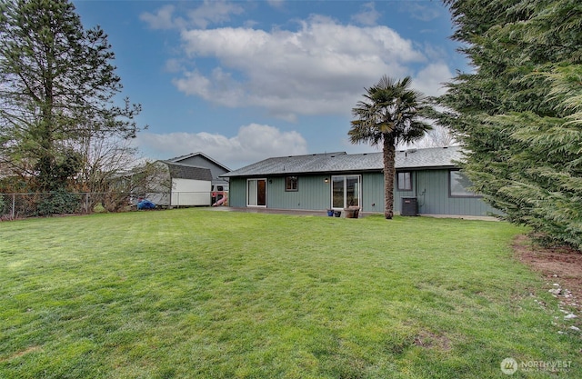 back of property with central AC and a lawn