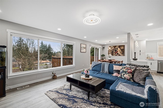 living room featuring light wood-style floors, a healthy amount of sunlight, and visible vents