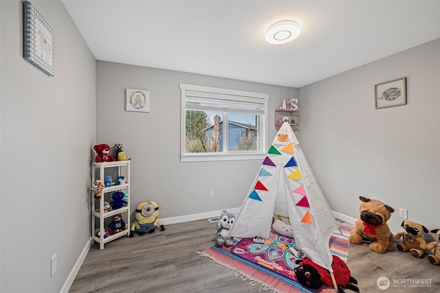 recreation room featuring baseboards and wood finished floors