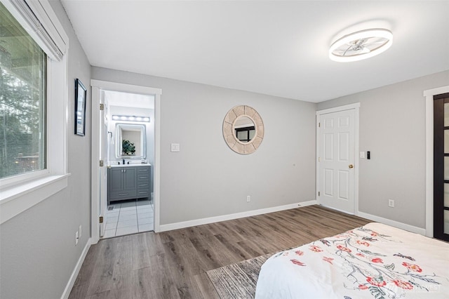 unfurnished bedroom featuring ensuite bath, baseboards, and wood finished floors