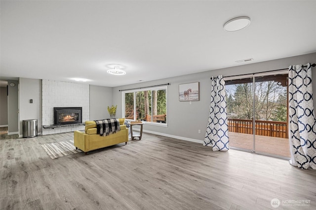 unfurnished living room with a fireplace, wood finished floors, visible vents, and baseboards