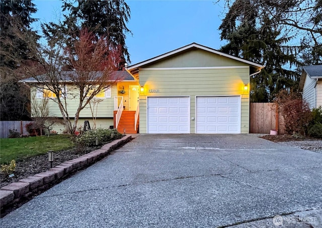 single story home with a garage, concrete driveway, and fence