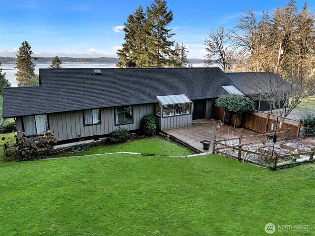 back of house with a garden, a shingled roof, a lawn, a deck with mountain view, and board and batten siding