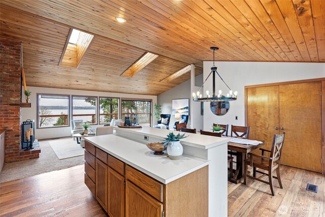 kitchen featuring a kitchen island, open floor plan, light countertops, brown cabinetry, and pendant lighting