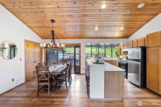 kitchen featuring light countertops, hanging light fixtures, freestanding refrigerator, a kitchen island, and vaulted ceiling