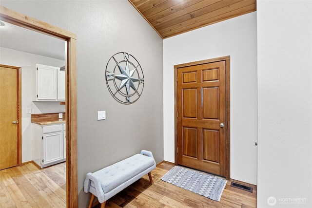 entryway with light wood-type flooring, wooden ceiling, visible vents, and baseboards