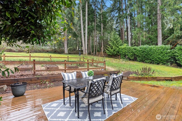 wooden deck featuring outdoor dining area and a lawn