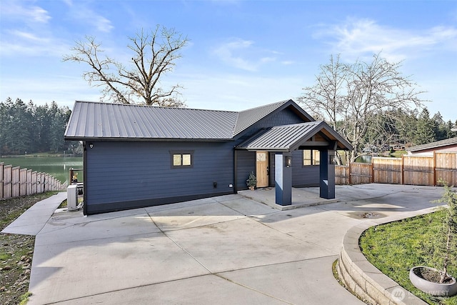 view of front facade featuring a water view, metal roof, fence, and a patio