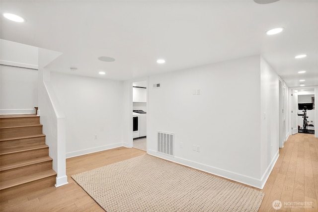 below grade area with light wood finished floors, baseboards, visible vents, stairway, and recessed lighting