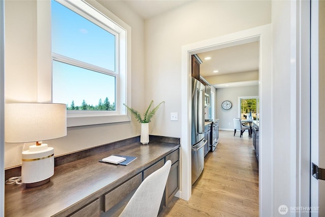 home office featuring light hardwood / wood-style floors and built in desk