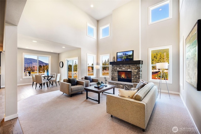 living room featuring a fireplace, light hardwood / wood-style flooring, a high ceiling, and a wealth of natural light