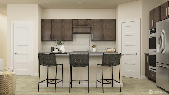 kitchen with a kitchen breakfast bar, light hardwood / wood-style flooring, dark brown cabinetry, and stainless steel appliances