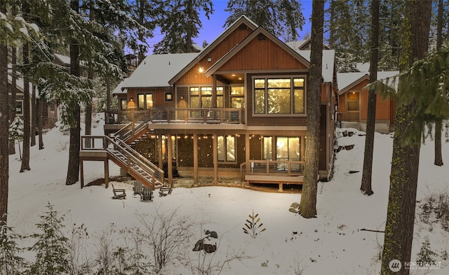 snow covered rear of property with stairway and a wooden deck