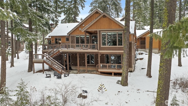 snow covered property with stairs and a deck