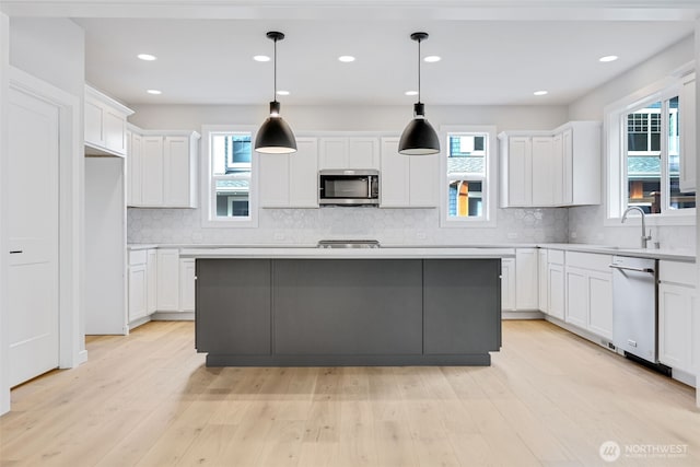 kitchen featuring white cabinets, stainless steel microwave, white built in refrigerator, light wood-style floors, and a wealth of natural light