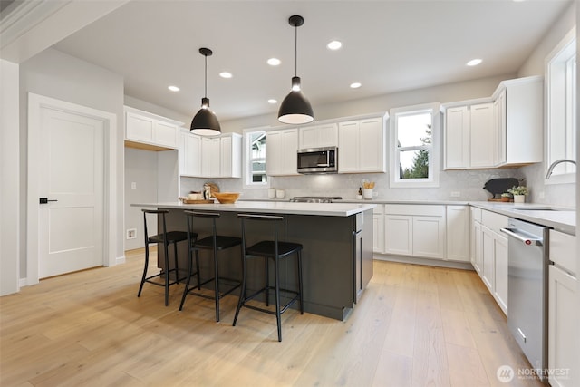 kitchen with appliances with stainless steel finishes, white cabinetry, a sink, and tasteful backsplash