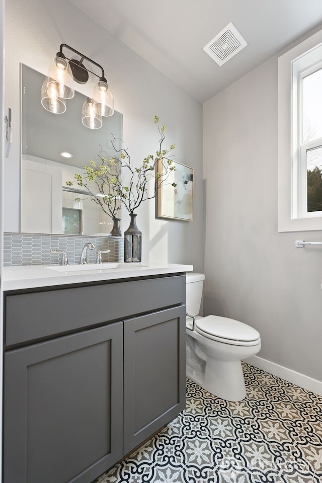 bathroom with tasteful backsplash, visible vents, baseboards, toilet, and vanity