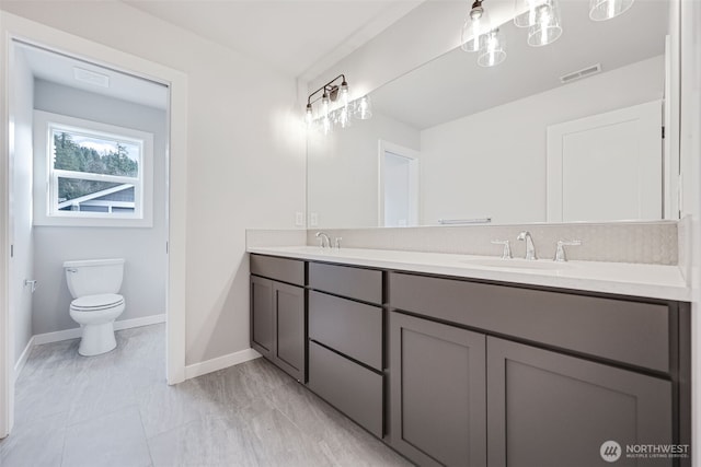 bathroom featuring toilet, double vanity, a sink, and visible vents