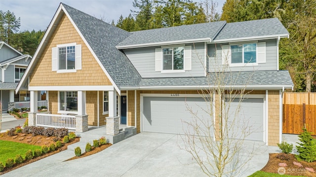 view of front of house with a garage, roof with shingles, covered porch, and fence