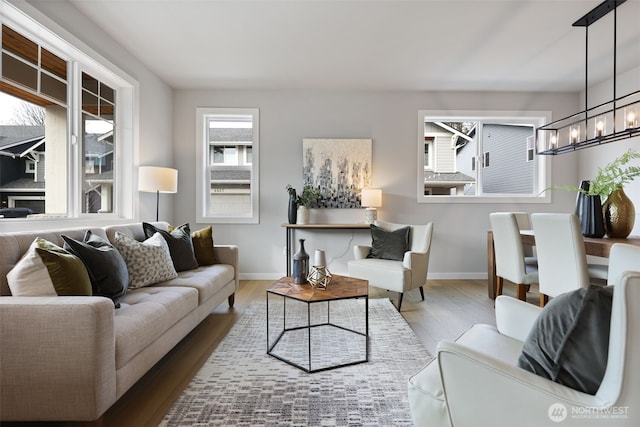 living area featuring baseboards, an inviting chandelier, and wood finished floors