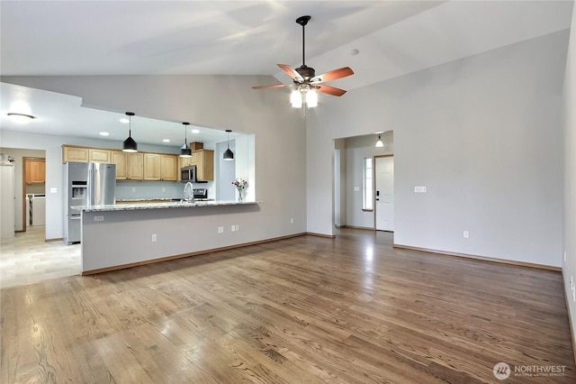 unfurnished living room featuring baseboards, ceiling fan, light wood-type flooring, high vaulted ceiling, and a sink