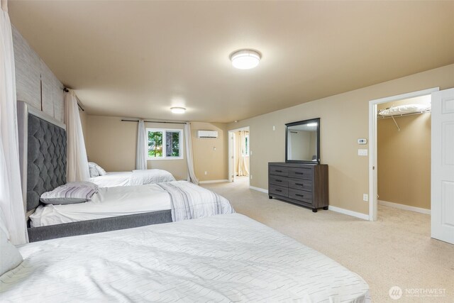 bedroom featuring a closet, a spacious closet, a wall mounted AC, light carpet, and baseboards