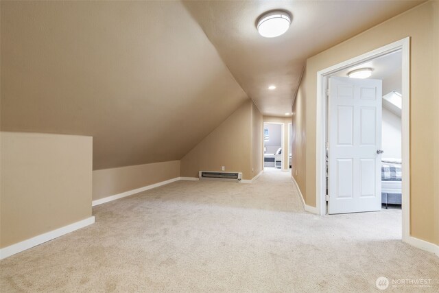 additional living space with lofted ceiling, light carpet, and baseboards