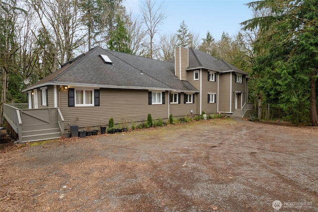 rear view of property featuring roof with shingles