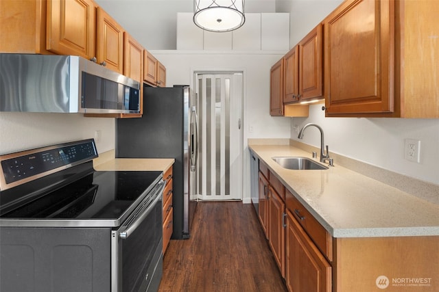 kitchen featuring light stone counters, dark wood-style floors, brown cabinets, appliances with stainless steel finishes, and a sink