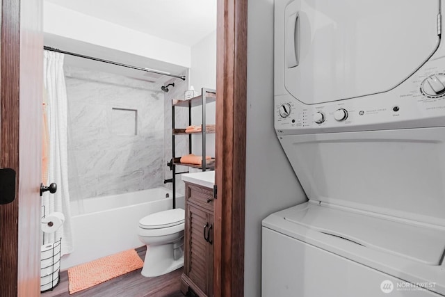 full bathroom with toilet, stacked washer and clothes dryer, shower / bath combo, hardwood / wood-style floors, and vanity