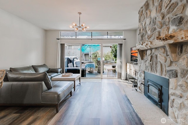 living room featuring a chandelier, a stone fireplace, and dark hardwood / wood-style floors