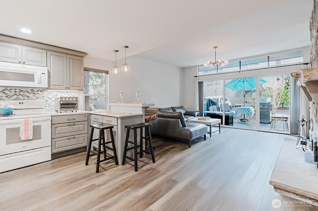 kitchen featuring white appliances, pendant lighting, backsplash, and light wood-type flooring