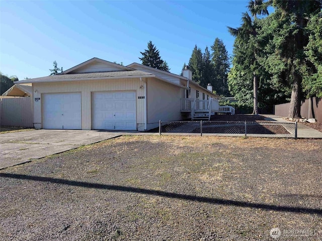 view of home's exterior featuring driveway, an attached garage, and fence